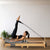 Frau trainiert am grauen TWHEELS Pilates Reformer aus Ahornholz im Home-Studio