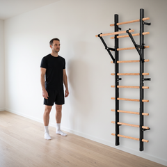 TWHEELS Sprossenwand mit Klimmzugstange an der Wand montiert neben einem stehenden Mann, mit sichtbarem Wandabstand und Bodenkontakt.