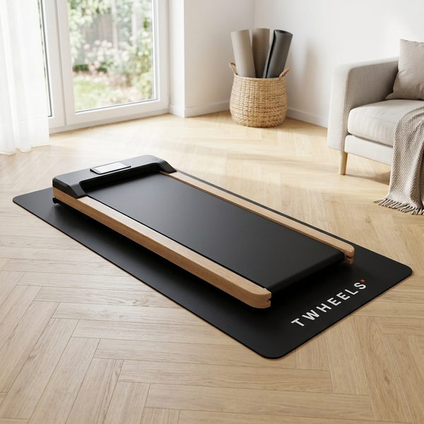 Il WalkingPad TWHEELS in legno di quercia è posizionato sul tappetino protettivo nero per pavimenti.